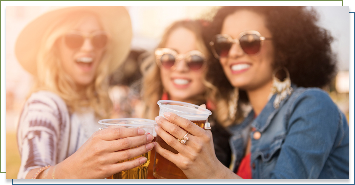 Group of women smiling and holding beers.